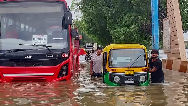 A man pushes an auto as it is stuck in a waterlogged road after heavy rainfall at Sethi village, in Surat. A man pushes an auto as it is stuck in a waterlogged road after heavy rainfall at Sethi village, in Surat.