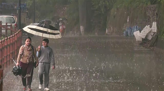 Commuters protect themselves amid heavy rainfall, in Shimla. Commuters protect themselves amid heavy rainfall, in Shimla.