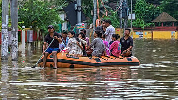 Fire and Emergency Services Assam personnel rescue stranded residents from a flood-hit area in Guwahati